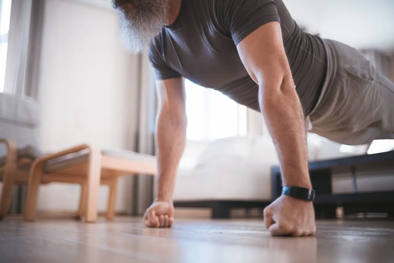 A man doing push-ups on his knuckles on a living room floor, his face out of frame