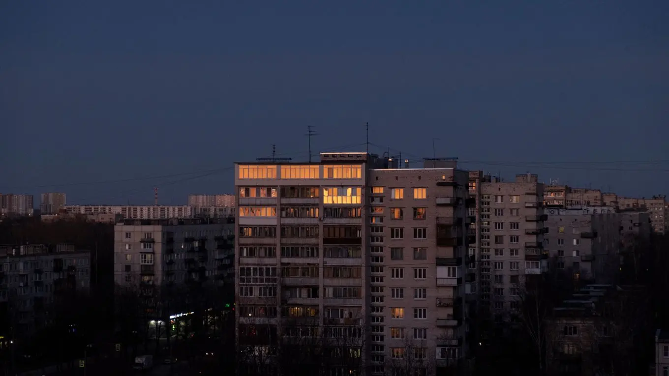 Apartment blocks against a dark blue sky, only a few windows lit