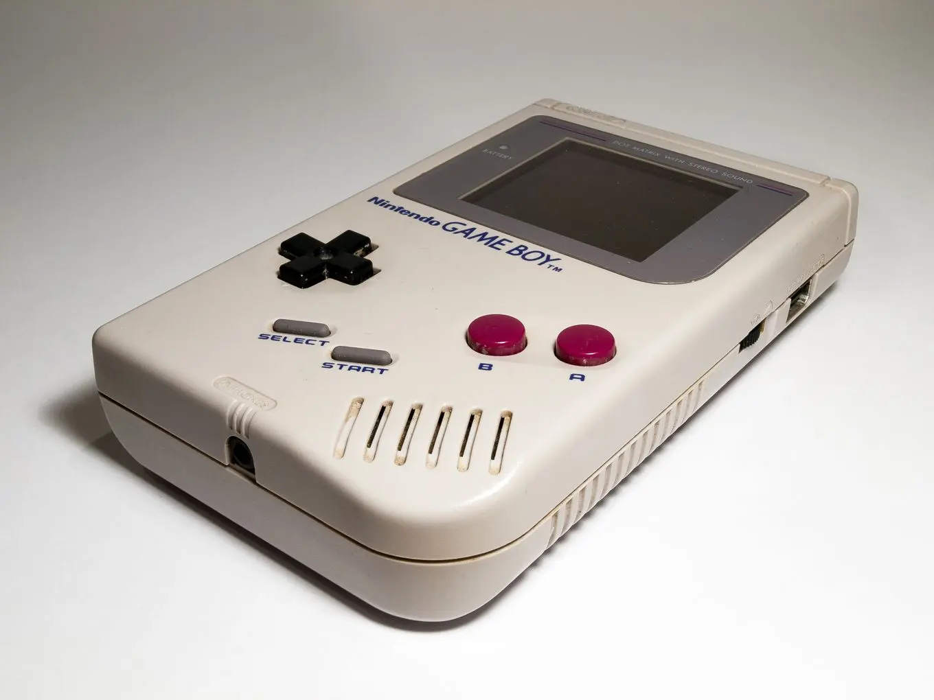 An original grey Nintendo Game Boy handheld console on a white surface