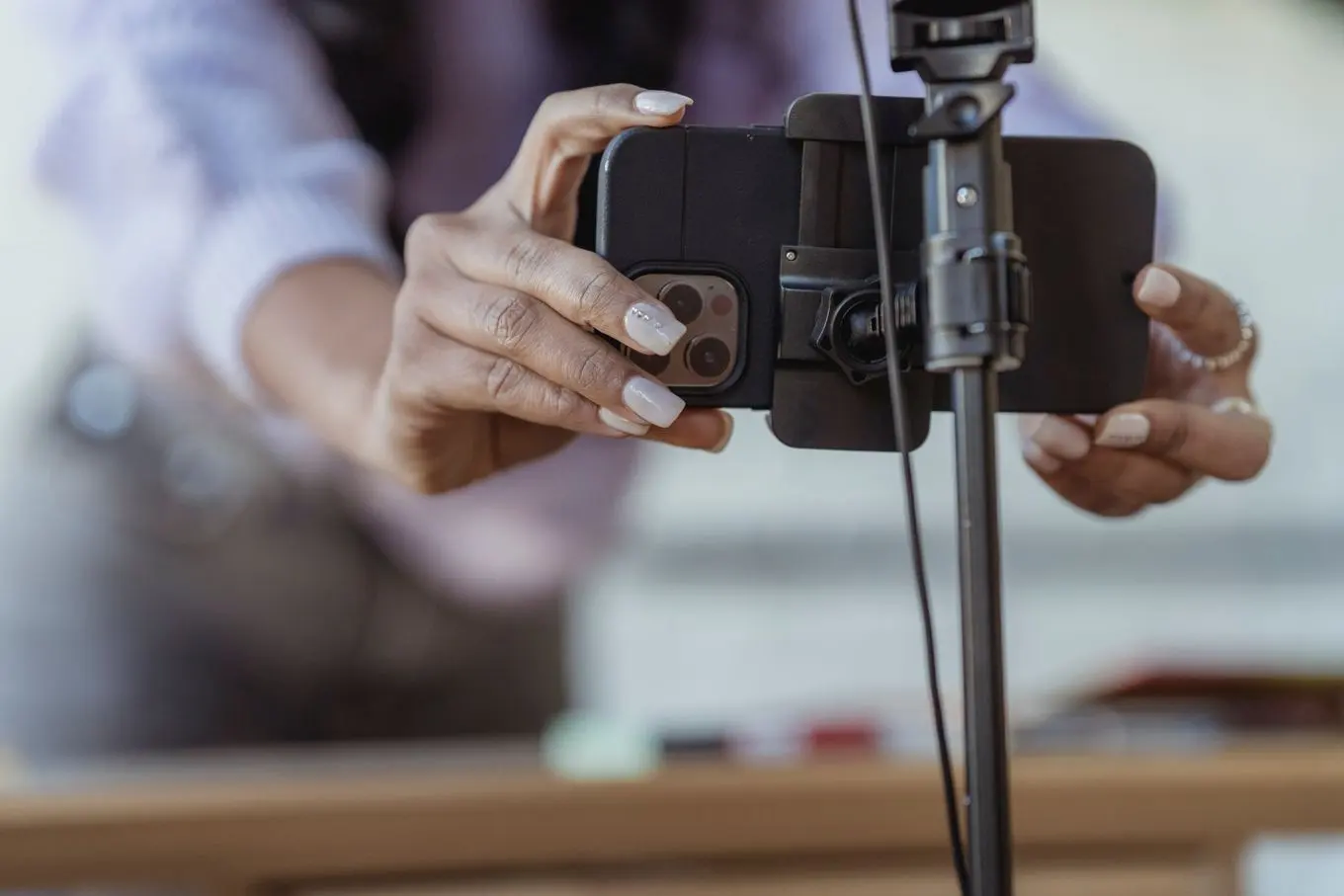 Two hands clipping a smartphone into a tripod mount