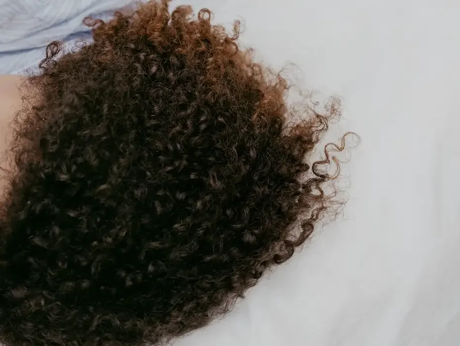 Curly hair on a white pillow: someone deep asleep, seen from above.