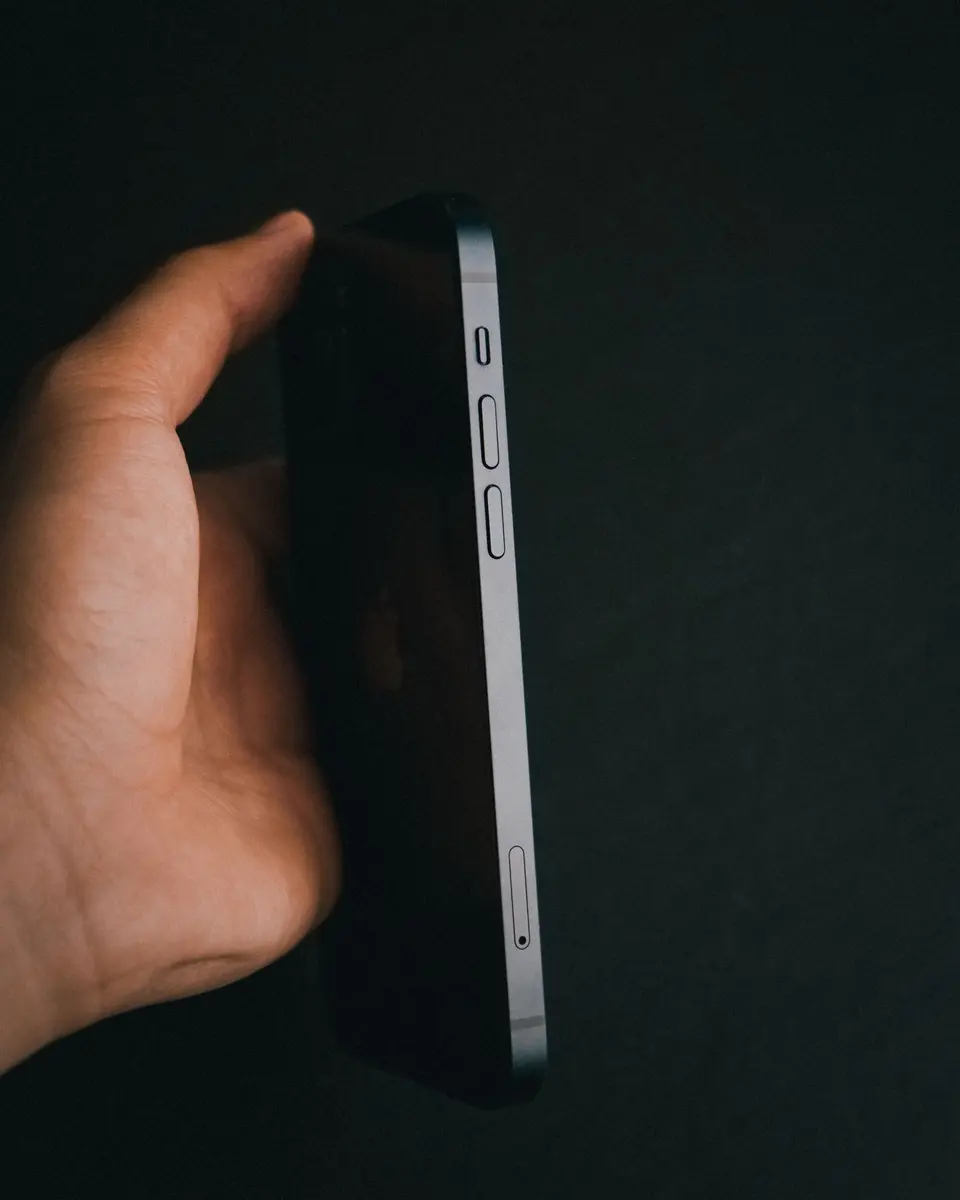 A hand holding an iPhone edge-on, its volume buttons in view.